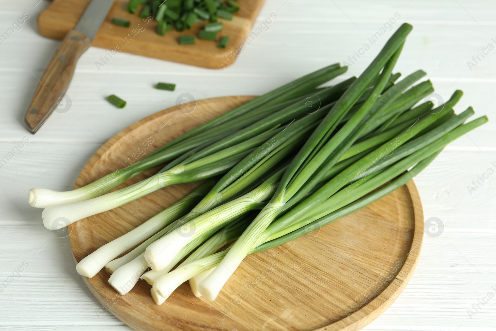 Photo of Fresh green spring onions on white wooden table