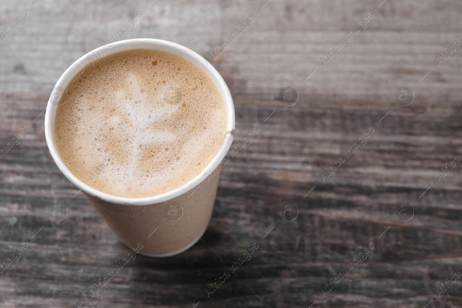 Photo of Coffee to go. Paper cup with tasty drink on wooden table, closeup. Space for text