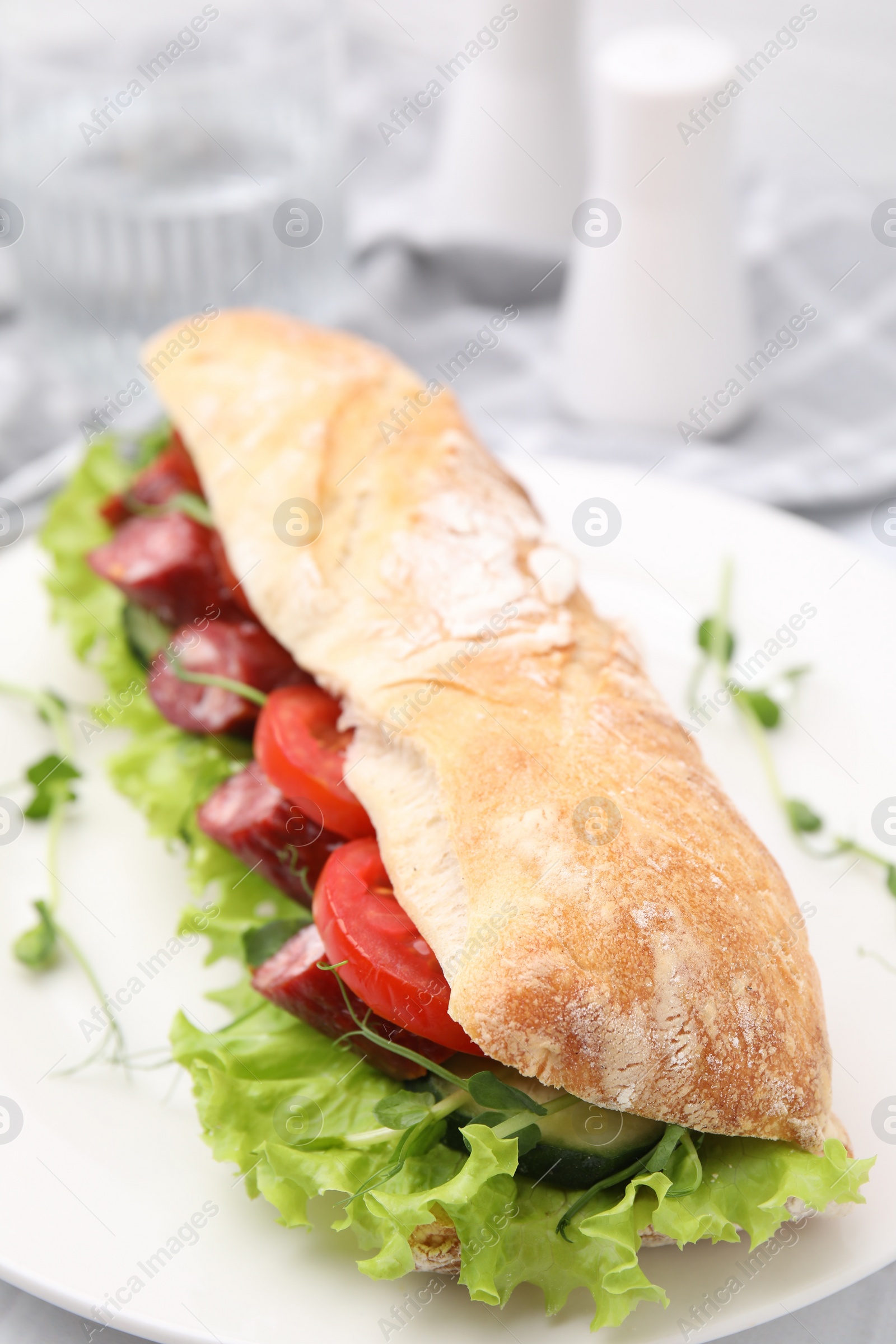 Photo of Delicious sandwich with sausages and vegetables on white table, closeup