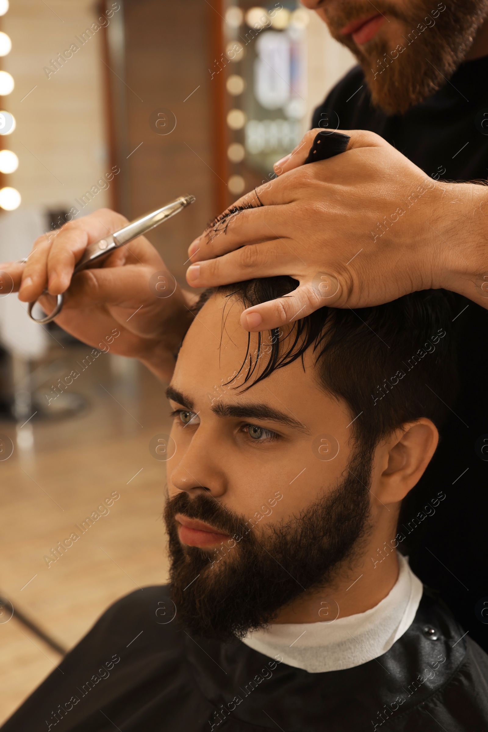 Photo of Professional hairdresser working with client in barbershop, closeup