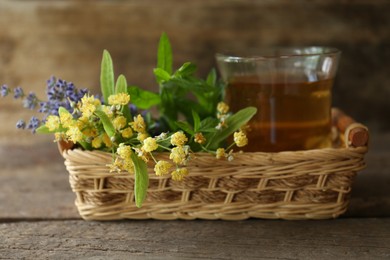 Tasty herbal tea, fresh lavender flowers and linden branches on wooden table, closeup