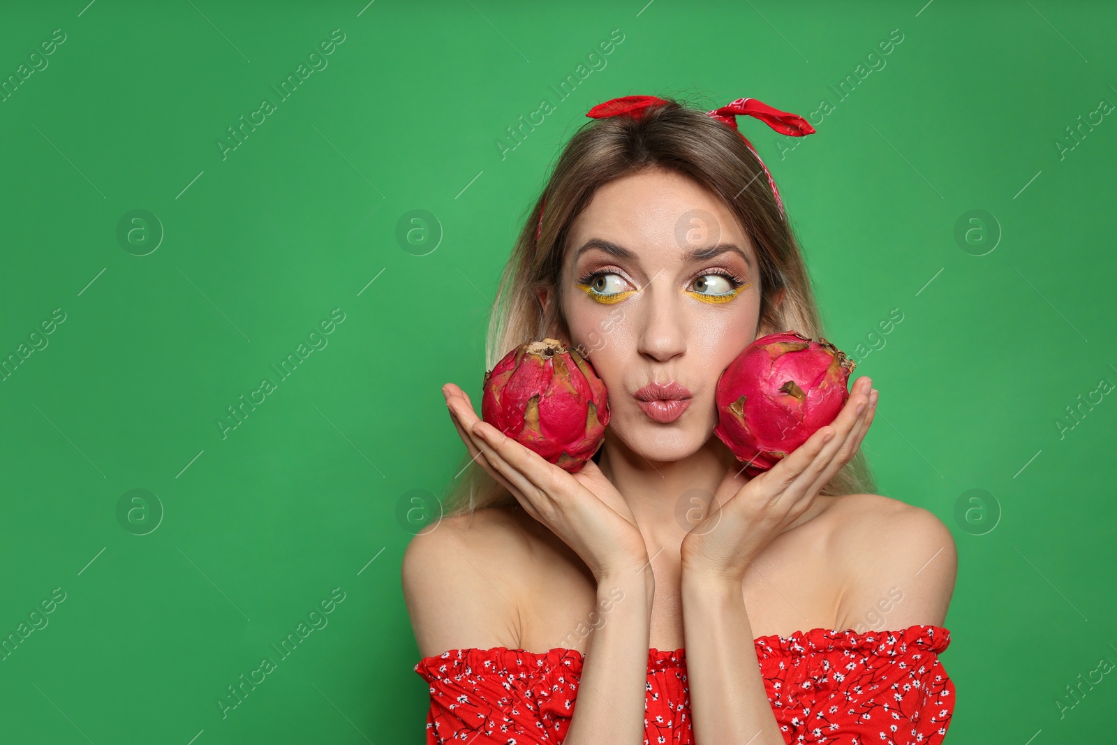 Photo of Young woman with fresh pitahayas on green background, space for text. Exotic fruits