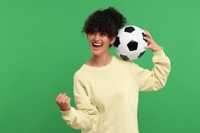 Happy fan with soccer ball celebrating on green background