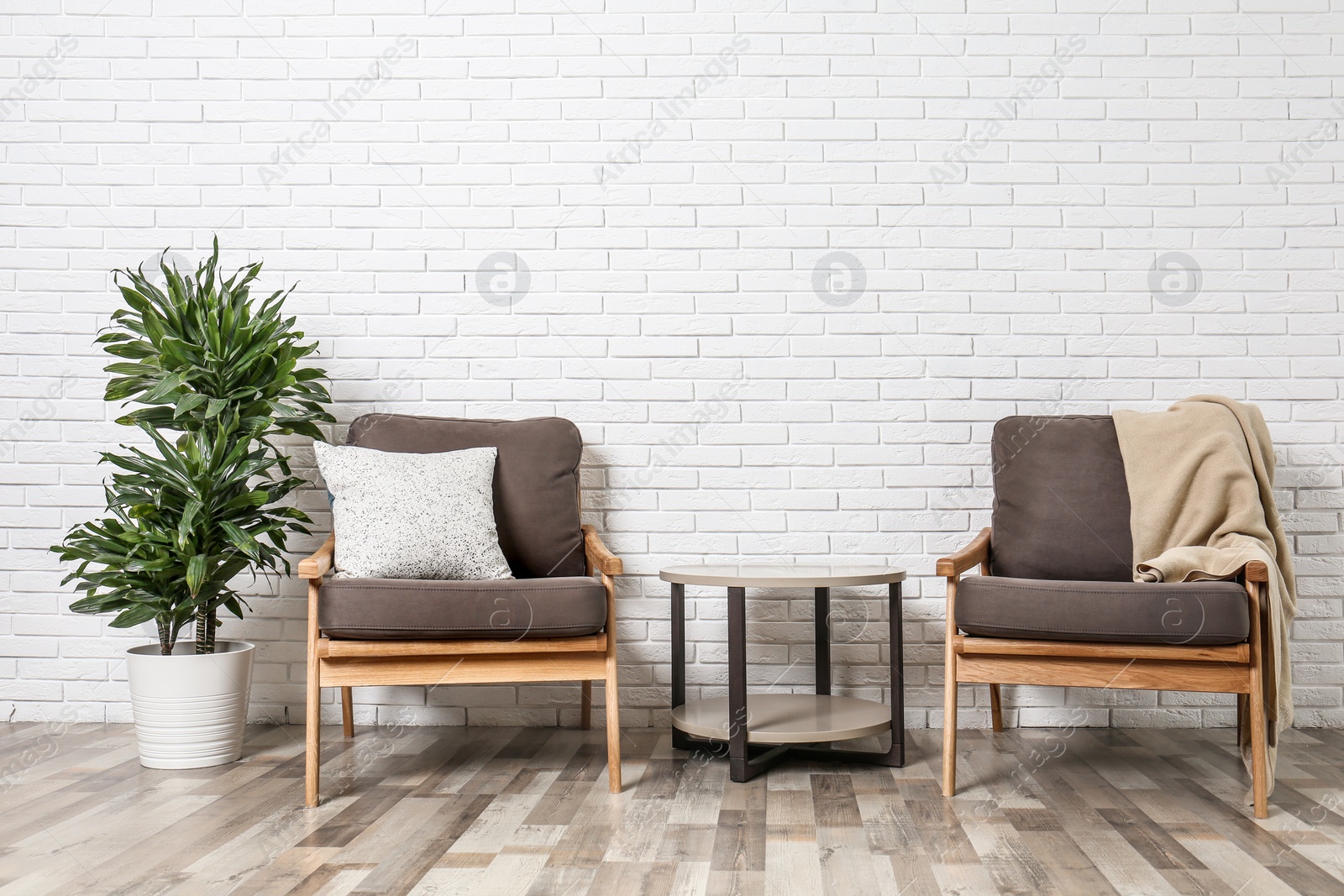 Photo of Room interior with modern armchairs and table near white brick wall