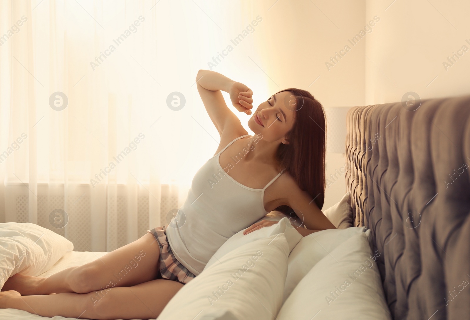 Photo of Young woman stretching on bed at home. Lazy morning
