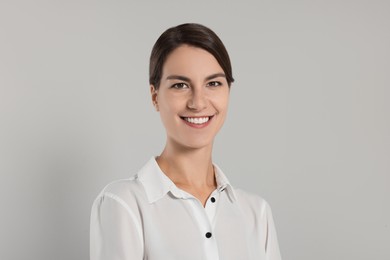 Portrait of happy secretary on light grey background