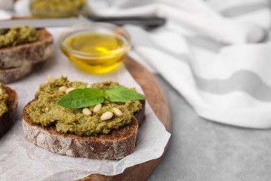 Tasty bruschettas with pesto sauce, nuts and fresh basil on light grey table, closeup. Space for text