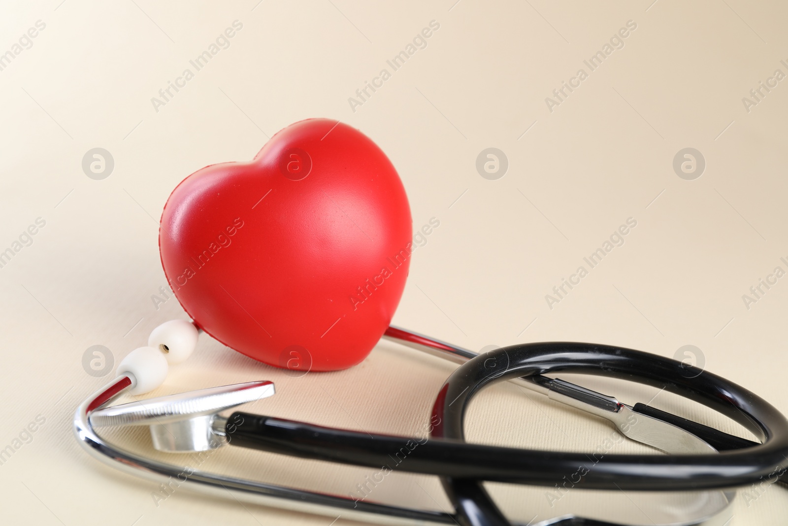 Photo of Stethoscope and red heart on beige background