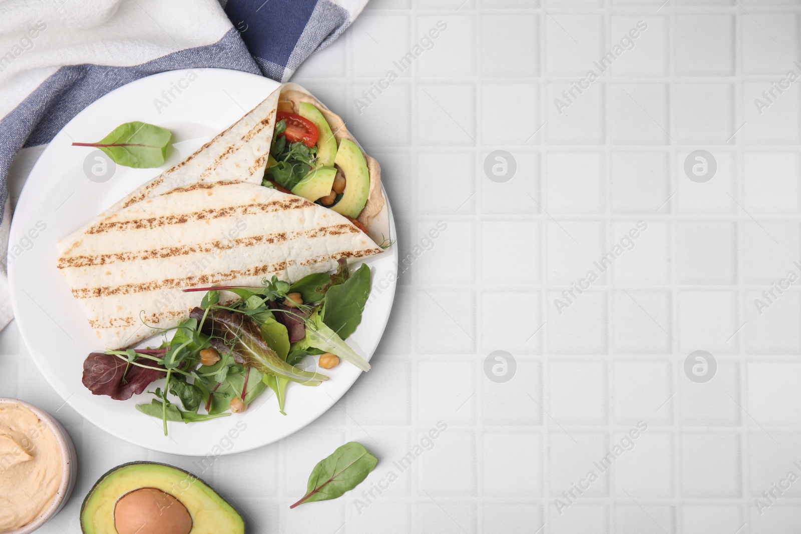 Photo of Plate with hummus wrap and vegetables on white table, flat lay. Space for text