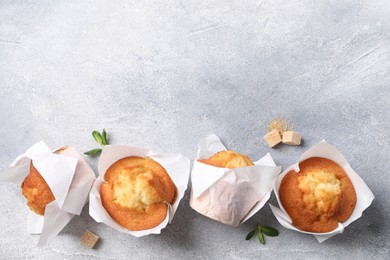 Delicious sweet muffins and brown sugar on light grey textured table, flat lay. Space for text