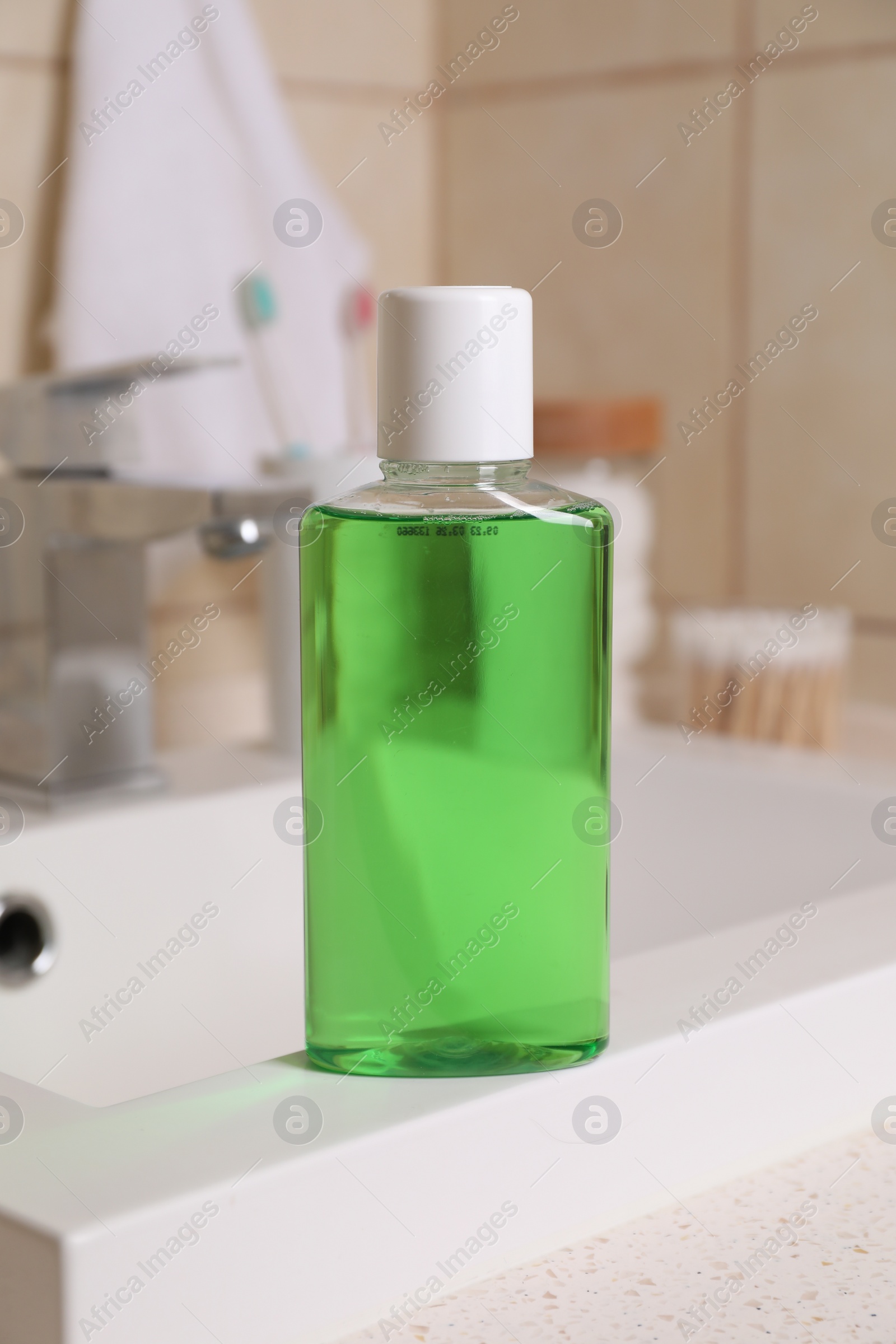 Photo of Fresh mouthwash in bottle on sink in bathroom, closeup