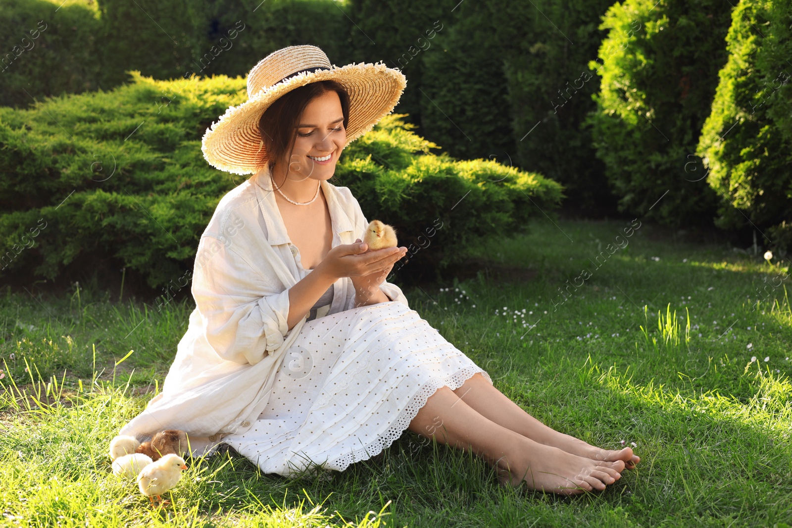 Photo of Beautiful woman with cute chick on green grass outdoors. Baby animal