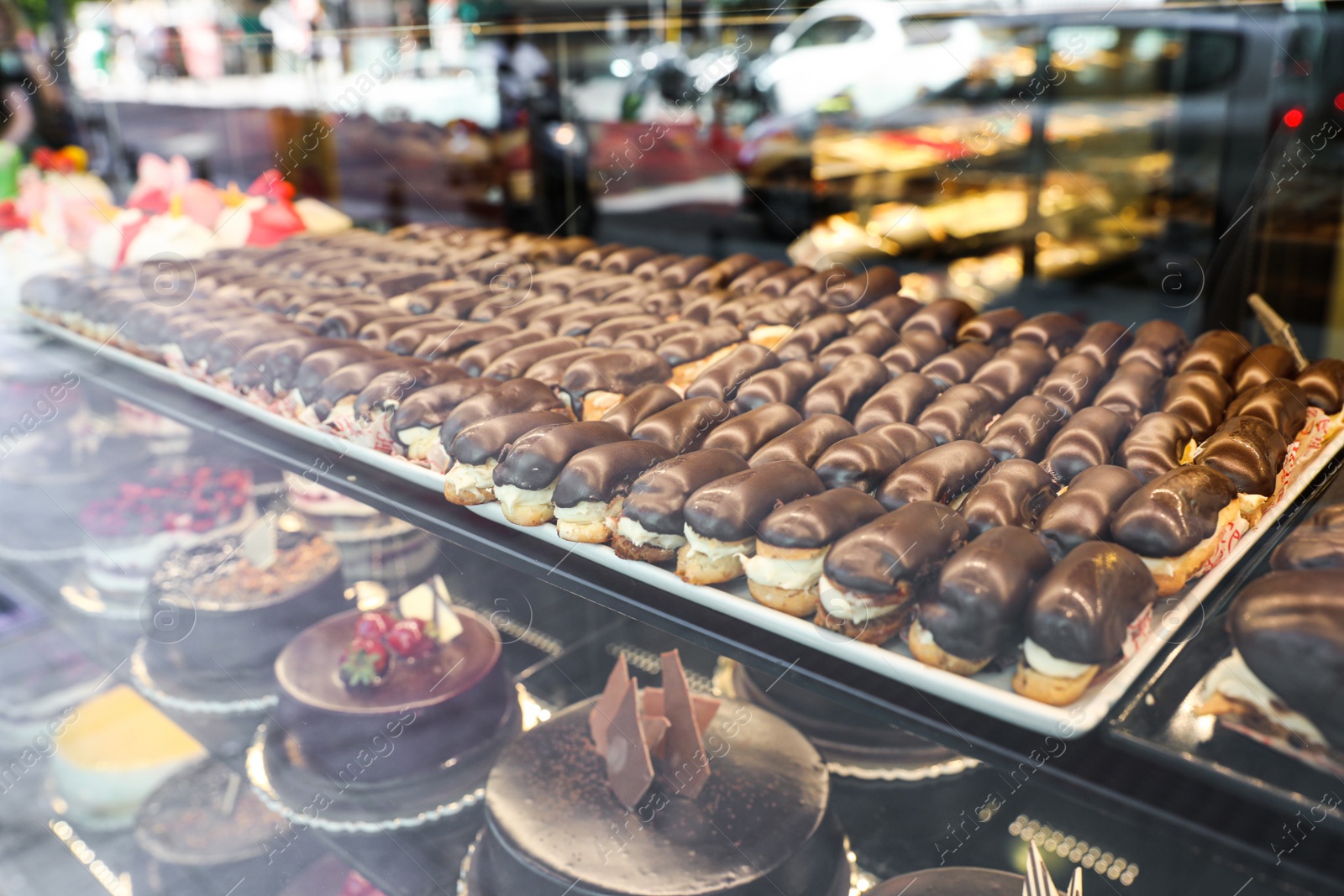 Photo of Different delicious cakes on display in cafe, view through window