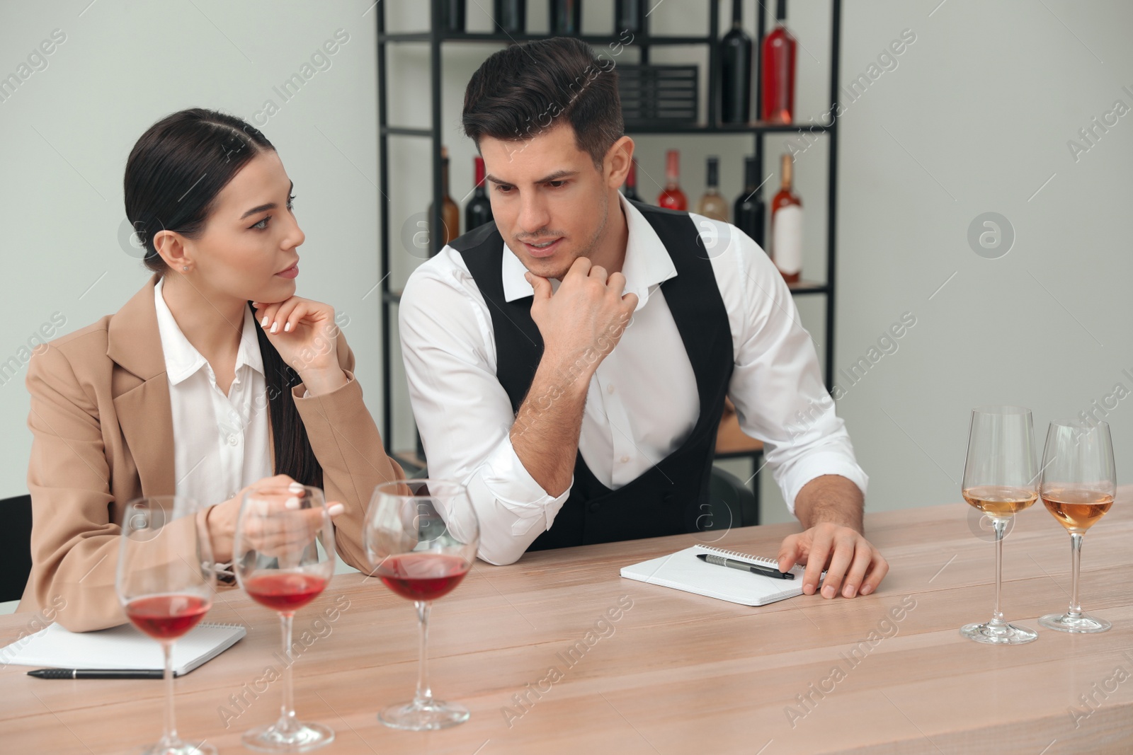 Photo of Sommeliers tasting different sorts of wine at table indoors