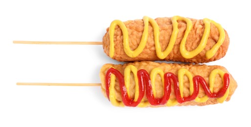 Delicious deep fried corn dogs with sauces on white background, top view