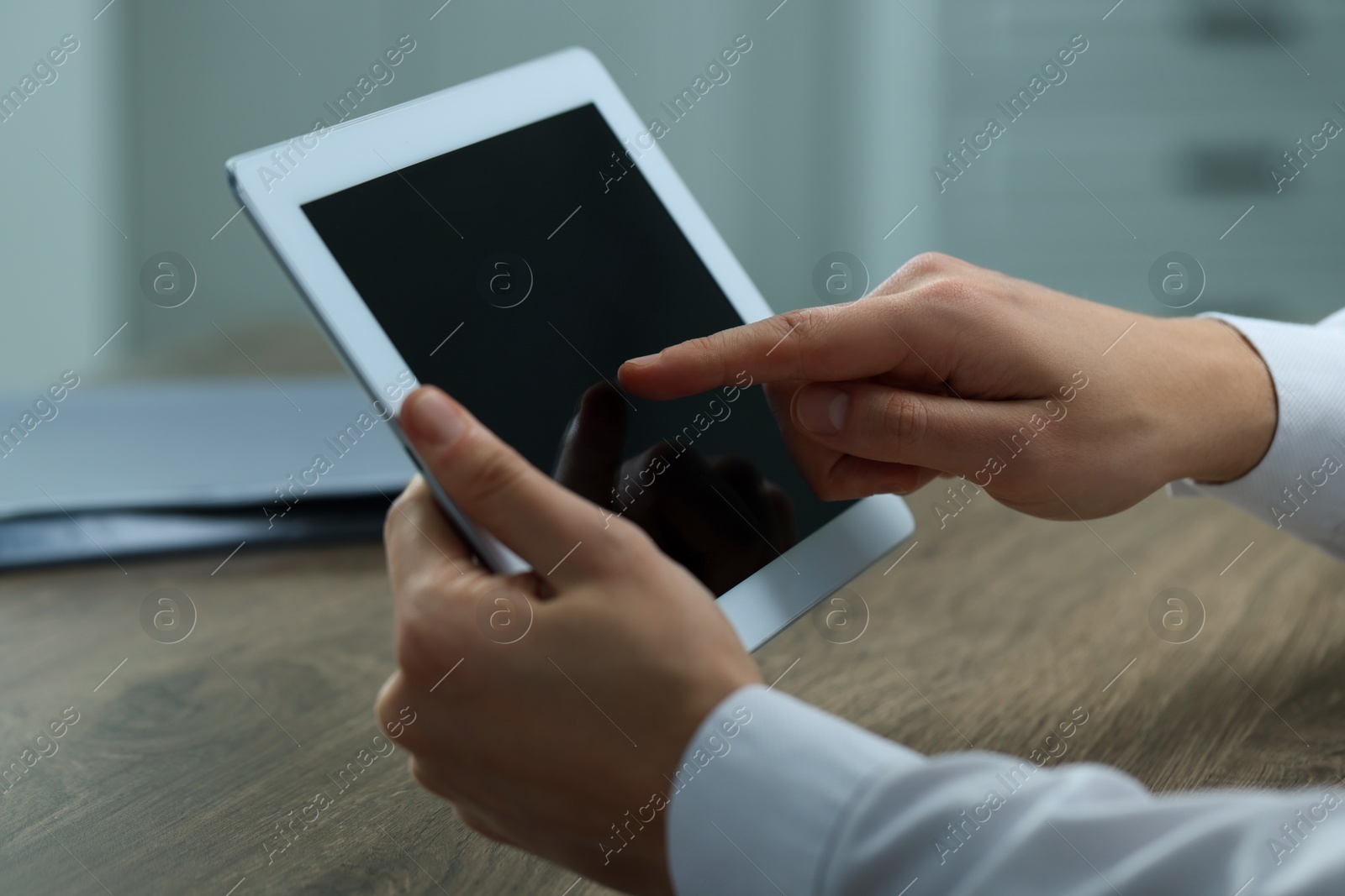Photo of Man using tablet at wooden table in office, closeup