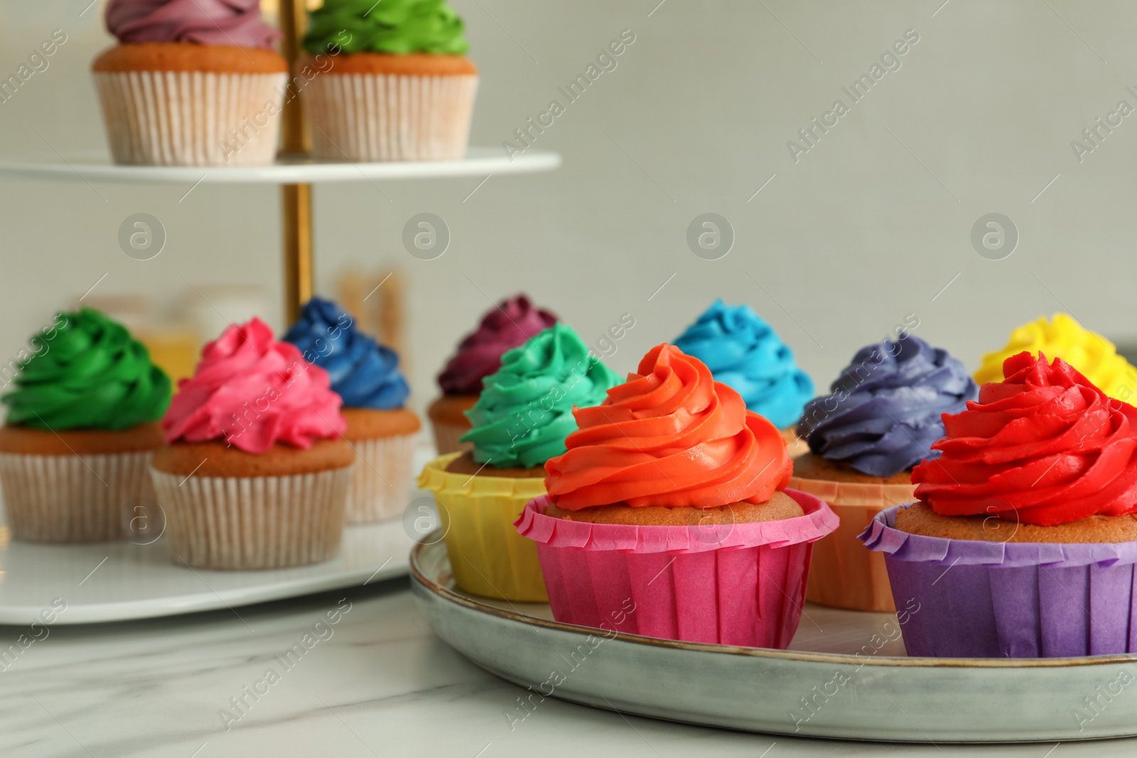 Photo of Delicious cupcakes with colorful cream on white table