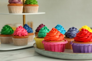 Delicious cupcakes with colorful cream on white table