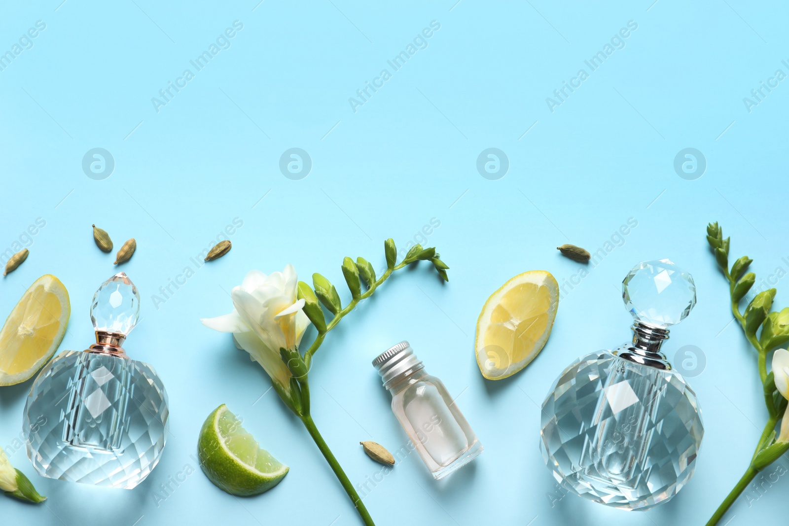 Photo of Flat lay composition with elegant perfumes on light blue background, space for text