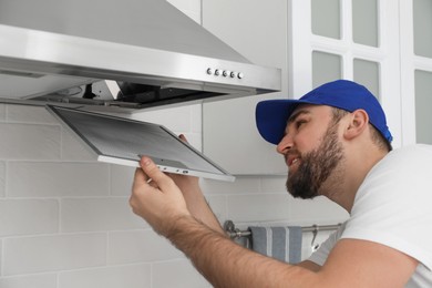 Worker repairing modern cooker hood in kitchen