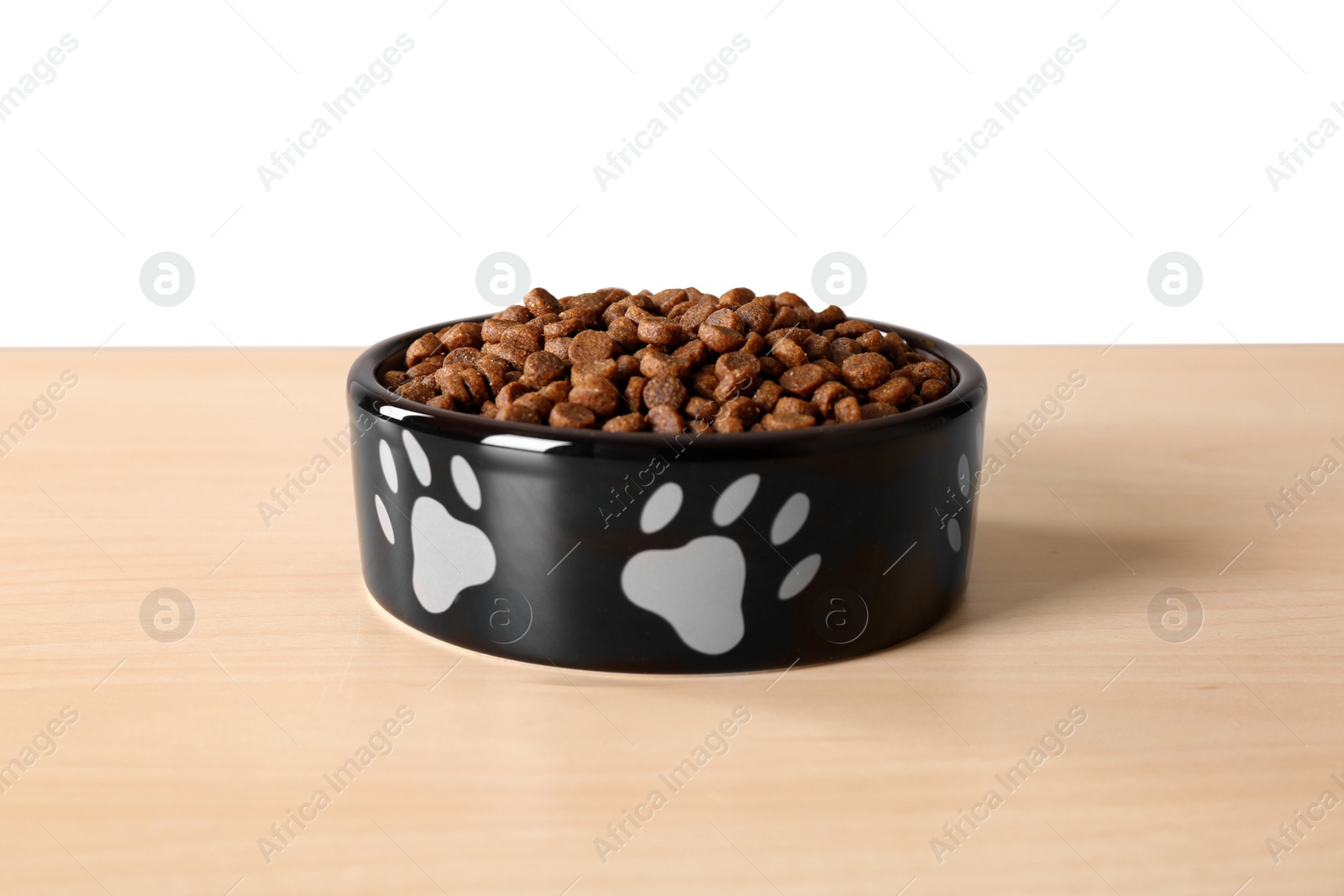 Photo of Dry dog food in pet bowl on wooden surface