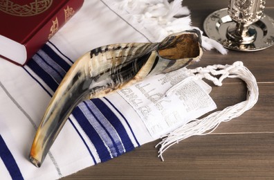 Photo of Shofar, Torah and tallit with text Pray For Peace To Jerusalem on wooden table. Rosh Hashanah holiday symbols