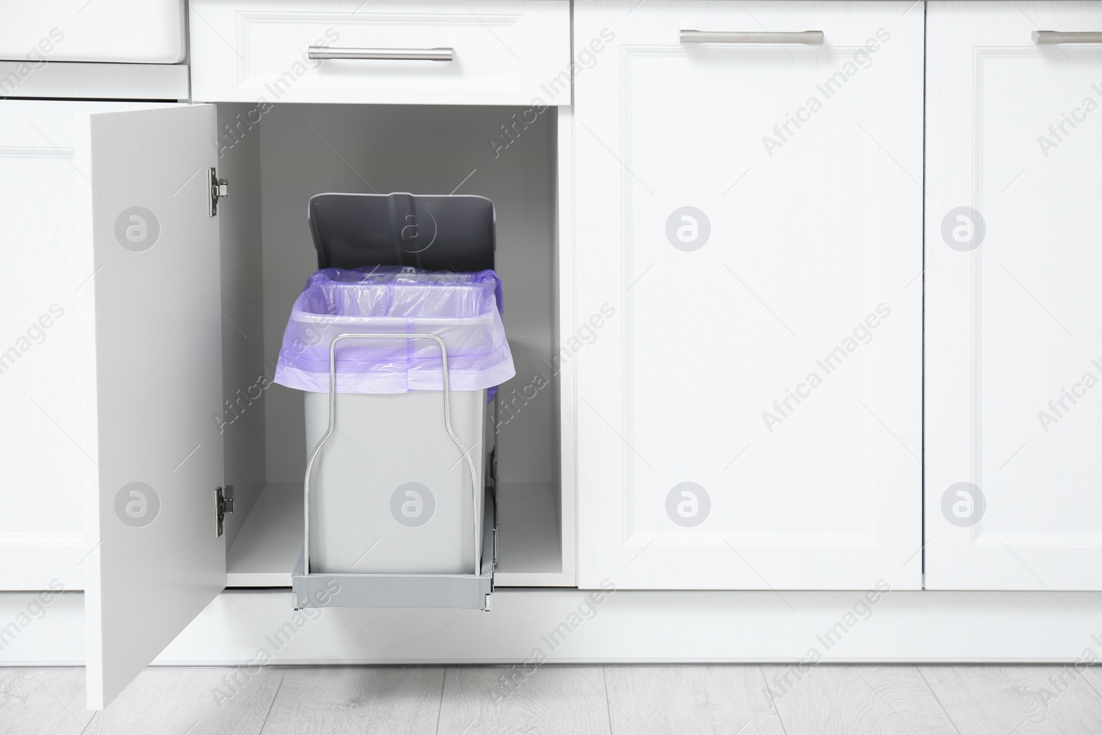 Photo of Open cabinet with trash bins in kitchen, space for text. Separate waste collection