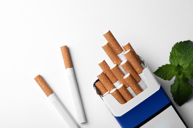 Photo of Menthol cigarettes and mint on white background, flat lay