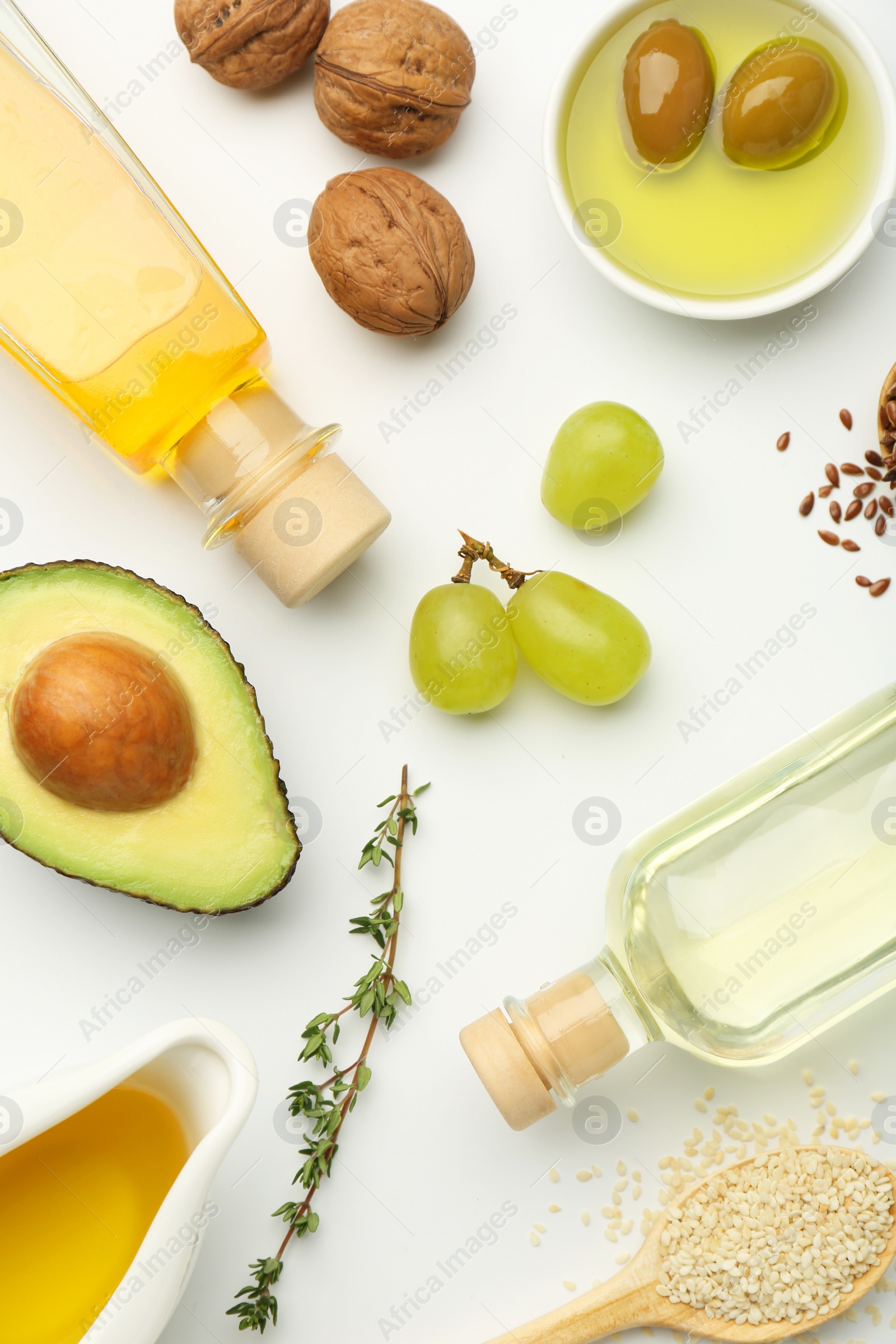 Photo of Vegetable fats. Different oils in glass bottles and ingredients on white table, flat lay