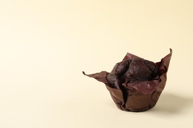 Photo of Tasty chocolate muffin on beige background, space for text