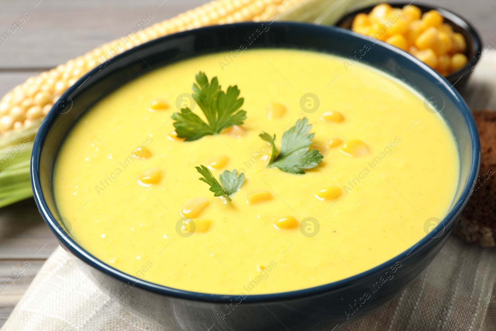 Photo of Delicious creamy corn soup served on table, closeup