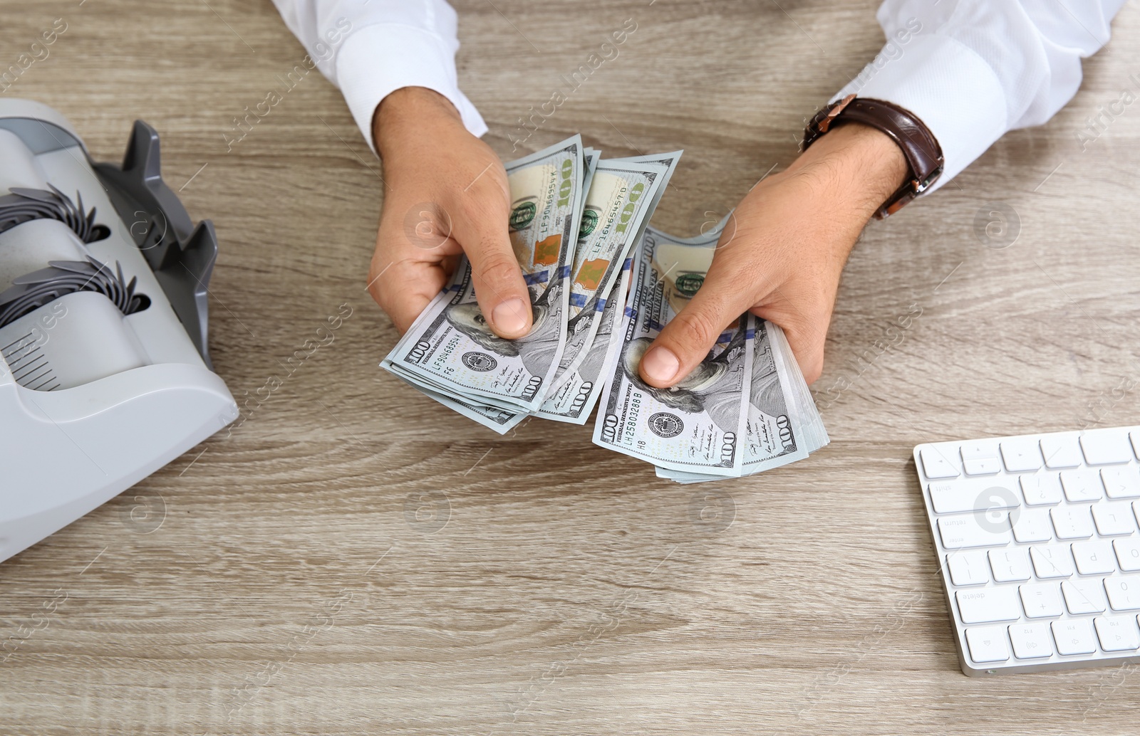 Photo of Male teller counting money at cash department, closeup