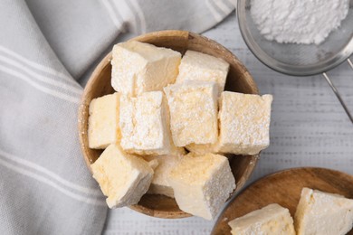 Photo of Tasty marshmallows with powder sugar on white wooden table, flat lay