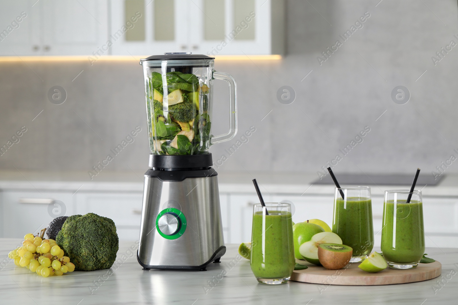 Photo of Delicious fresh smoothie and blender with ingredients on white marble table in kitchen