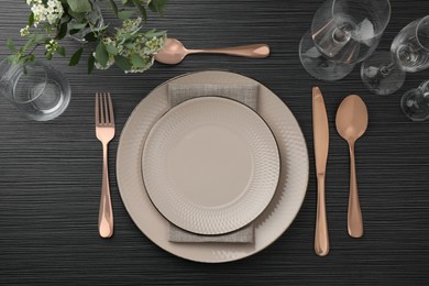 Photo of Stylish setting with cutlery, glasses and plates on black wooden table, flat lay