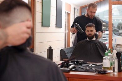 Photo of Professional hairdresser working with bearded client in barbershop