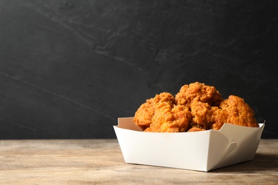 Tasty deep fried chicken pieces on wooden table. Space for text