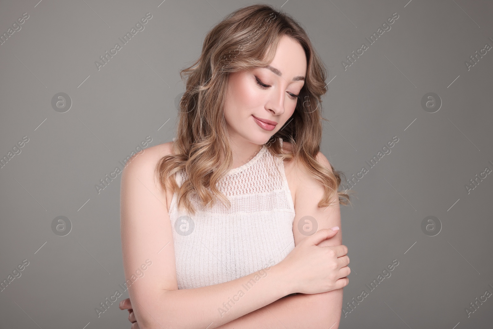 Photo of Portrait of beautiful woman with curly hair on grey background