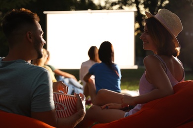 Photo of Young couple with popcorn watching movie in open air cinema. Space for text