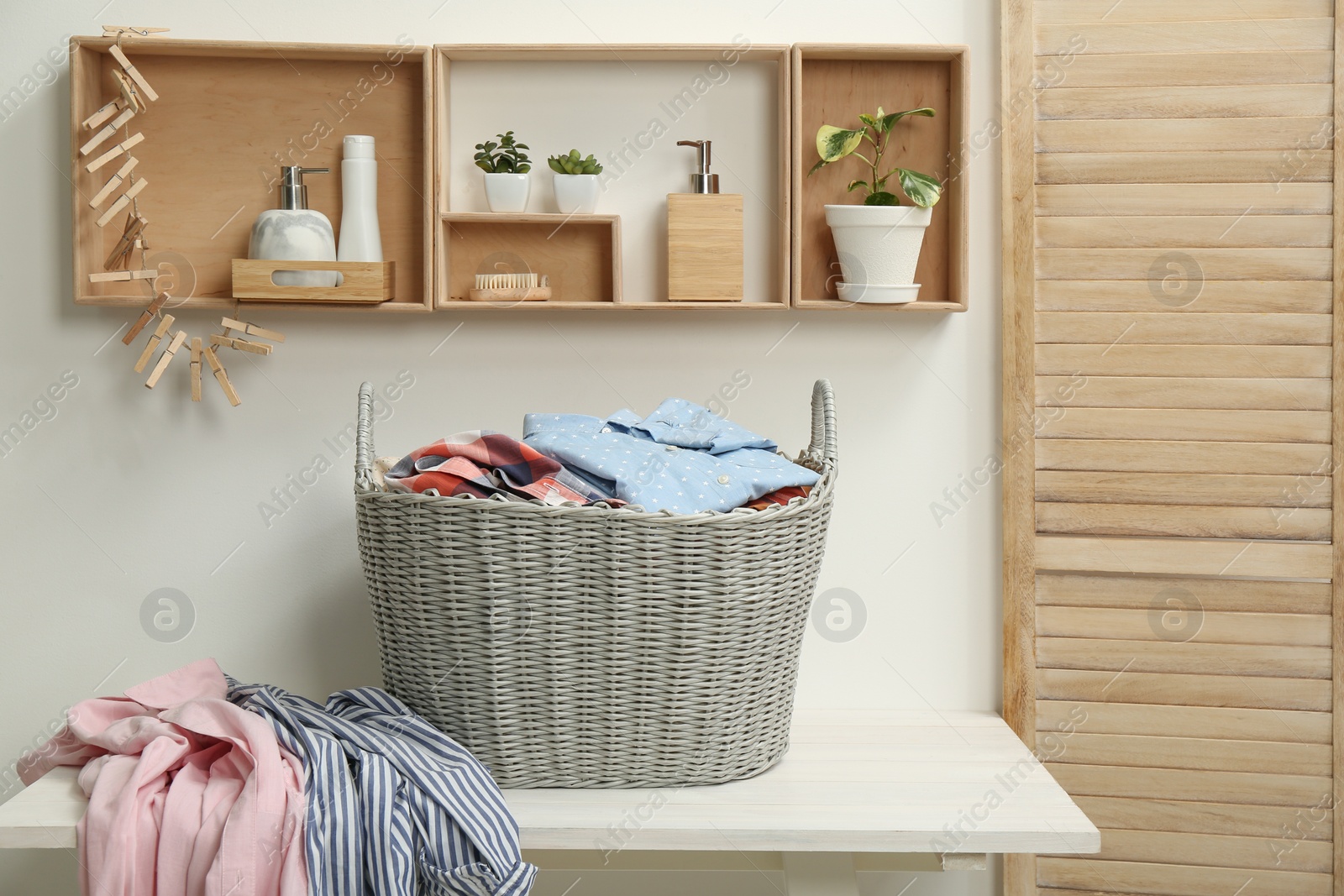 Photo of Wicker basket with dirty laundry on white table in bathroom