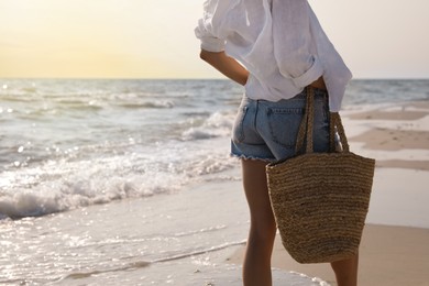 Woman with beach bag on sunlit seashore, closeup
