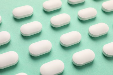 Photo of Many white pills on green background, closeup