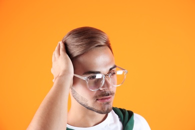 Young man with trendy hairstyle on color background