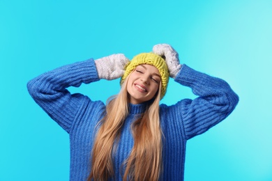 Photo of Portrait of emotional young woman in stylish hat, sweater and mittens on color background. Winter atmosphere