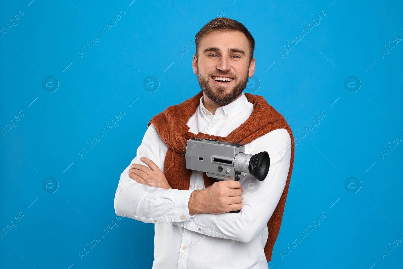 Photo of Young man with vintage video camera on light blue background