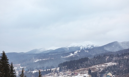 Photo of Winter landscape with mountain village near conifer forest