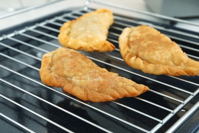 Delicious fried chebureki with tasty filling on metal grid