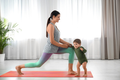 Photo of Young woman doing exercise with her son indoors. Home fitness