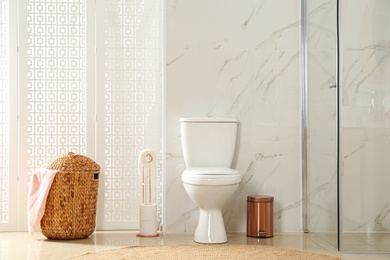 Toilet bowl near shower stall in modern bathroom interior