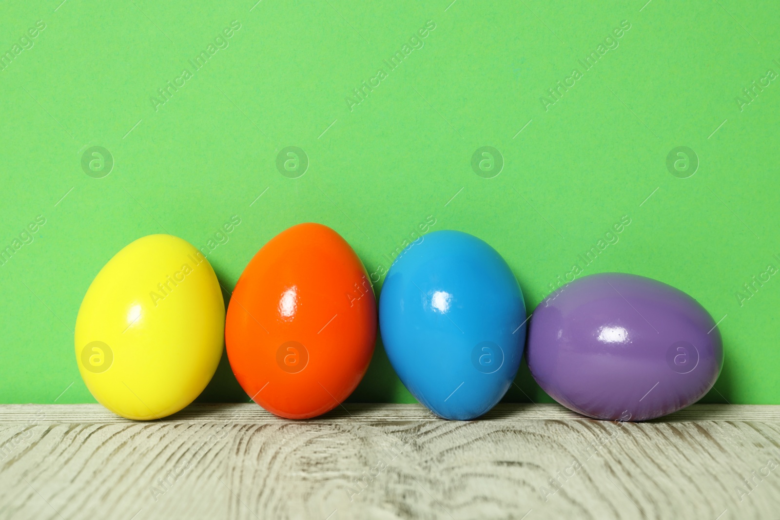 Photo of Easter eggs on white wooden table against green background